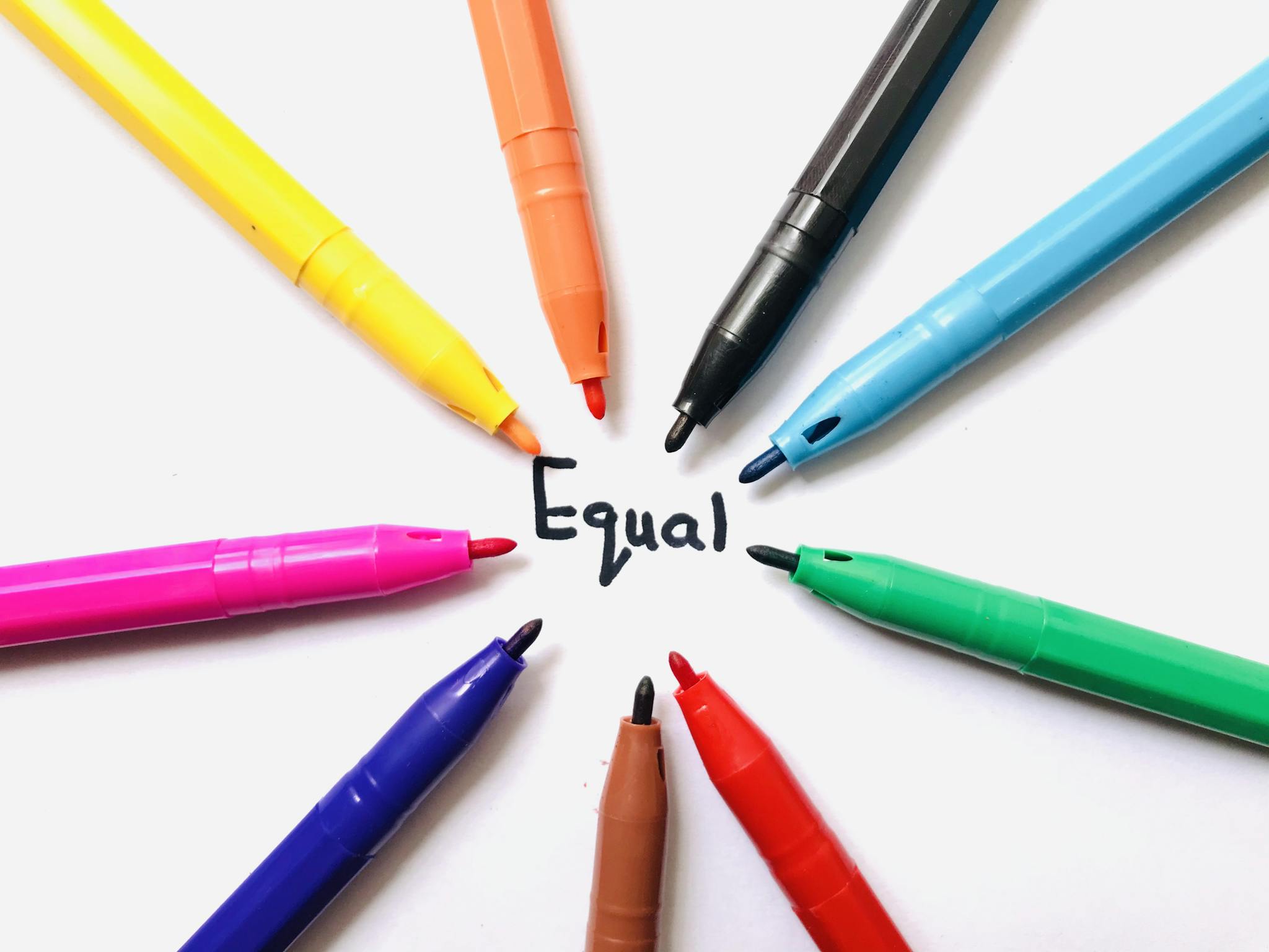 Colorful markers arranged in a circle on white paper around the word 'Equal'.
